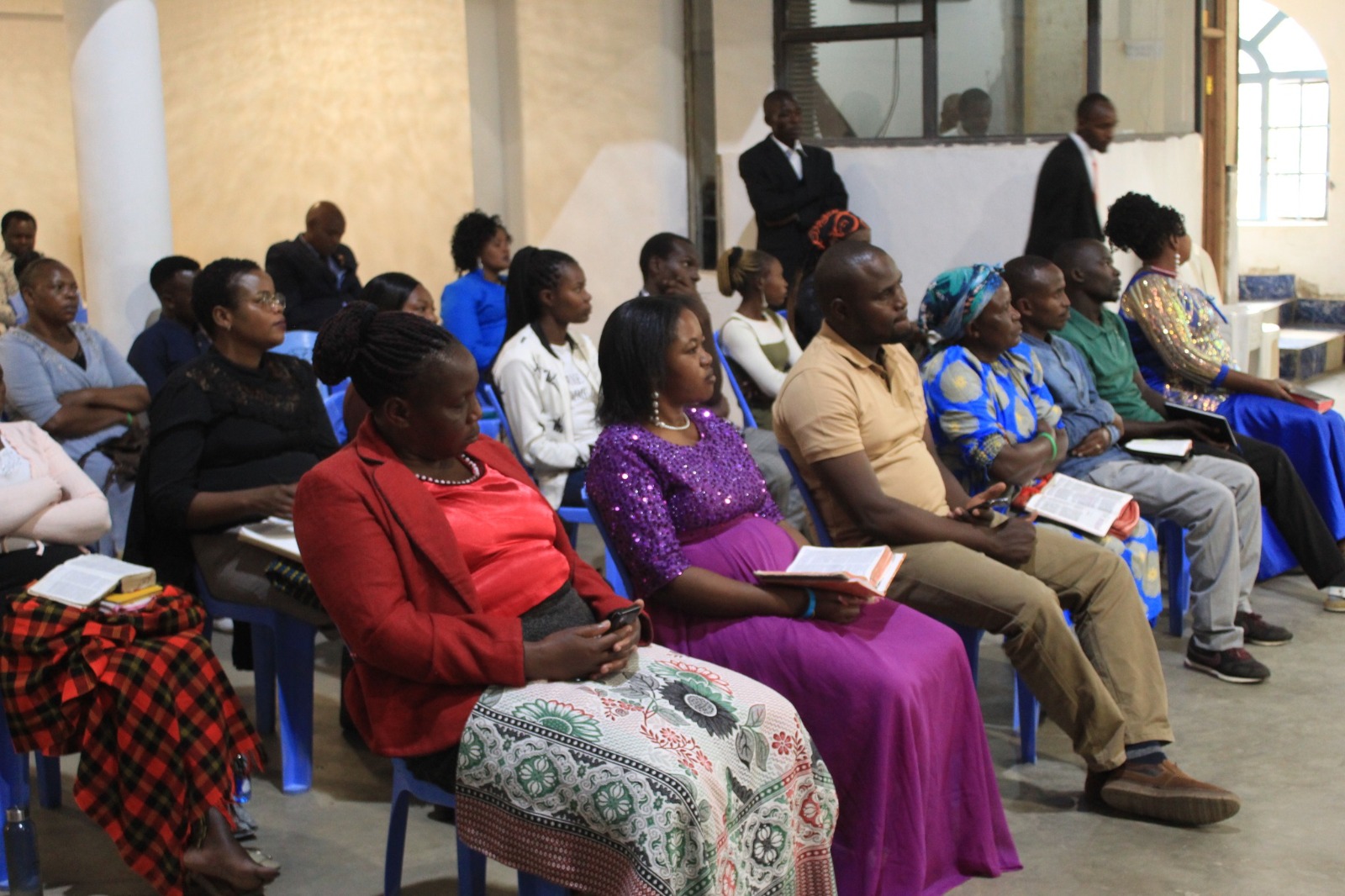 Faithful congregation engaged in worship during church service with blue chairs and spiritual fellowship