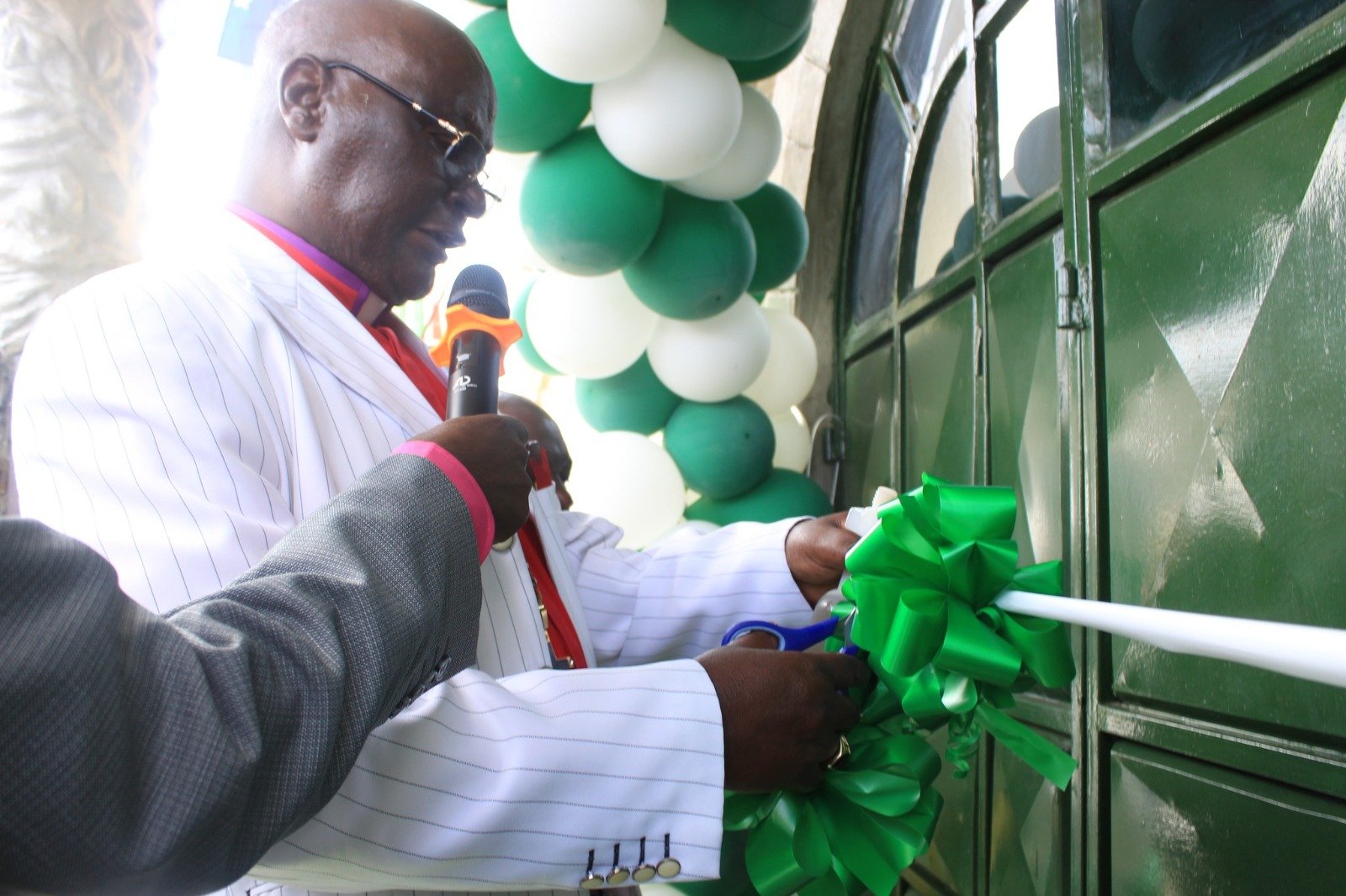 Pastor cutting ribbon during church opening ceremony with traditional green ribbon and community celebration